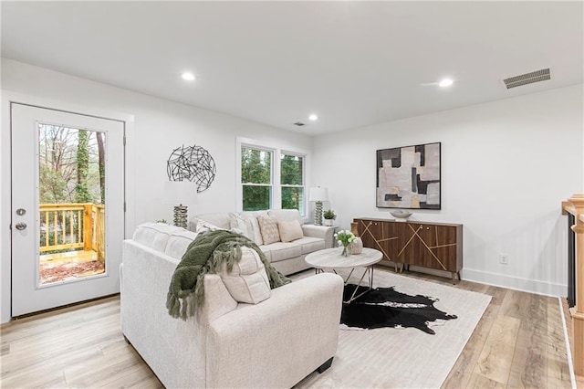 living room with recessed lighting, visible vents, light wood-style flooring, and baseboards