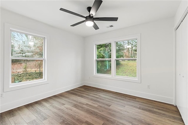 empty room featuring a wealth of natural light, baseboards, and wood finished floors