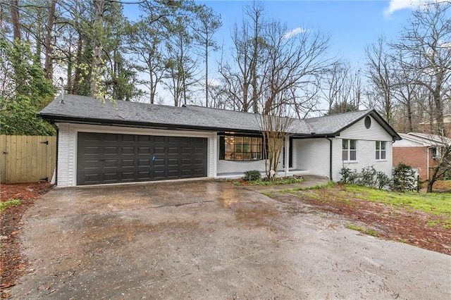 view of front facade featuring fence, concrete driveway, an attached garage, a shingled roof, and brick siding