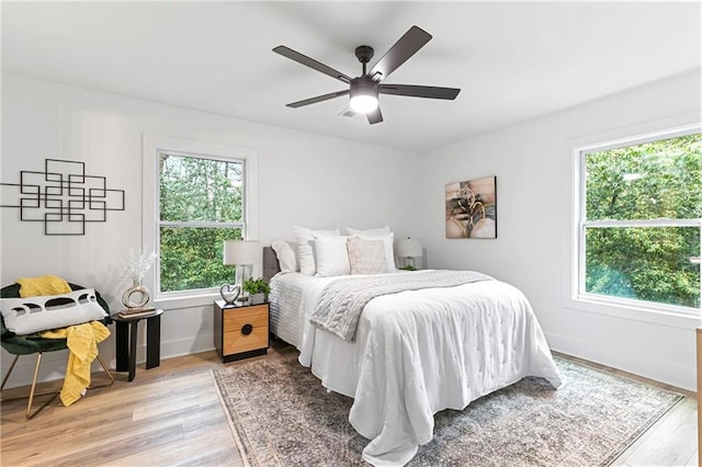 bedroom with a ceiling fan, light wood-type flooring, and baseboards