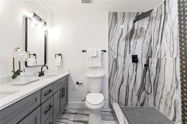 full bathroom with a marble finish shower, toilet, double vanity, marble finish floor, and a sink