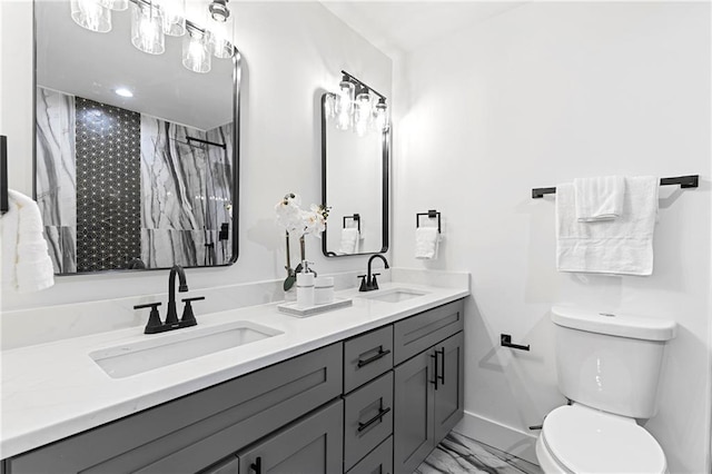 full bath featuring double vanity, toilet, marble finish floor, and a sink