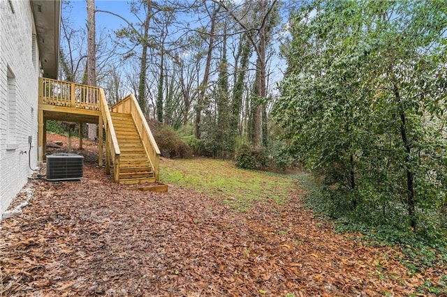 view of yard with central AC unit, a deck, and stairs