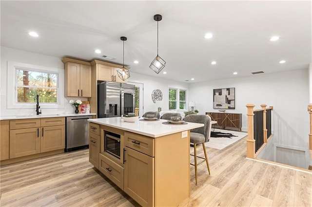 kitchen featuring a sink, light wood-style flooring, a kitchen bar, and stainless steel appliances