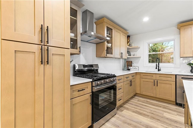 kitchen featuring a sink, wall chimney range hood, light brown cabinets, and stainless steel appliances