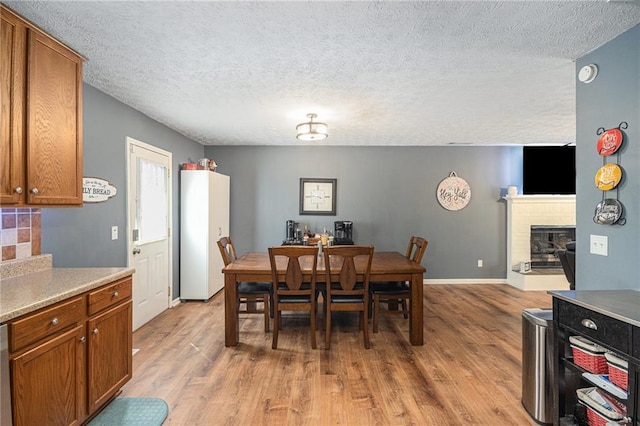 6355 Queens Rd, Douglasville, GA 30135 - dining area with a brick fireplace, light wood-style floors, baseboards, and a textured ceiling