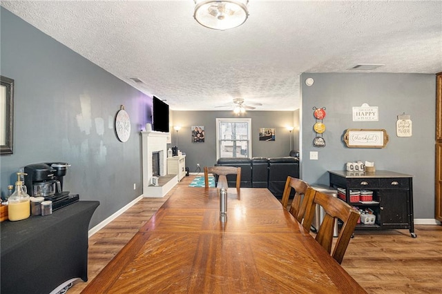 6355 Queens Rd, Douglasville, GA 30135 - dining space featuring visible vents, a fireplace with raised hearth, wood finished floors, and a ceiling fan