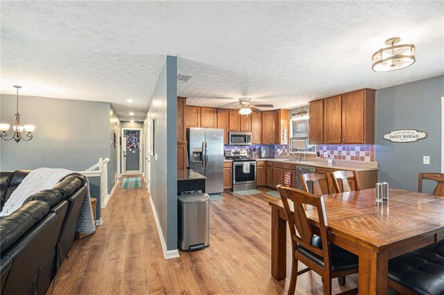 6355 Queens Rd, Douglasville, GA 30135 - kitchen featuring tasteful backsplash, brown cabinetry, light wood-type flooring, and appliances with stainless steel finishes