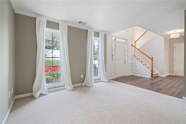 carpeted entrance foyer with baseboards, stairway, and ornamental molding