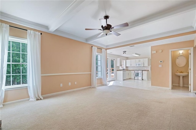 unfurnished living room featuring light colored carpet, beamed ceiling, plenty of natural light, ceiling fan, and baseboards