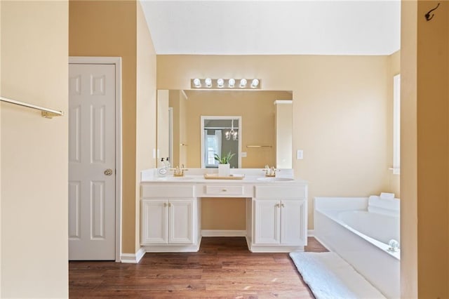 full bath featuring a bath, wood finished floors, double vanity, and a chandelier
