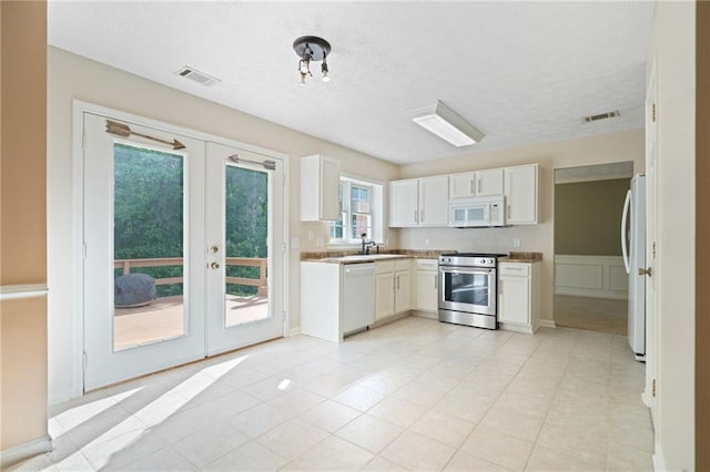 kitchen featuring white appliances, french doors, white cabinets, a textured ceiling, and light countertops
