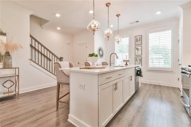 kitchen featuring a sink, visible vents, an island with sink, a kitchen bar, and light countertops