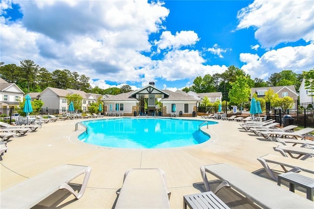 pool featuring fence, a patio area, and a residential view