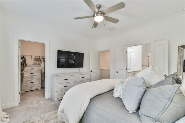 bedroom featuring a closet, a walk in closet, ensuite bathroom, light carpet, and ornamental molding