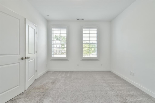 unfurnished room featuring light colored carpet, visible vents, and baseboards