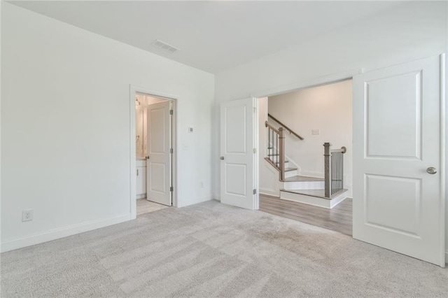 carpeted spare room featuring baseboards, stairs, and visible vents