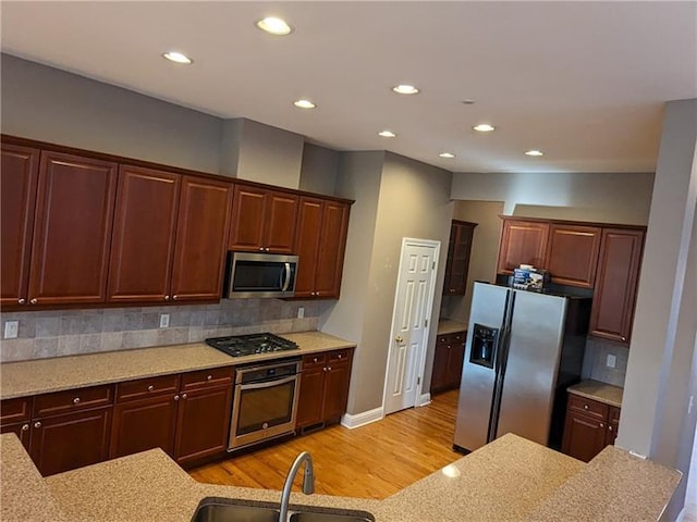 kitchen with tasteful backsplash, appliances with stainless steel finishes, light wood-style floors, a sink, and recessed lighting