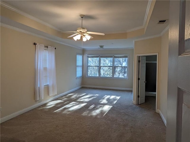 unfurnished bedroom with carpet floors, ornamental molding, a raised ceiling, and visible vents