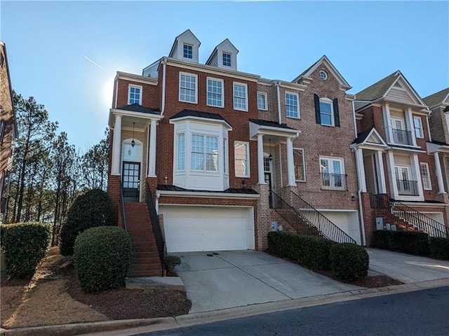 multi unit property featuring driveway, a garage, stairs, and brick siding