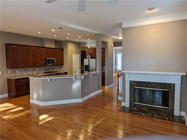 kitchen with decorative backsplash, appliances with stainless steel finishes, a kitchen breakfast bar, and wood finished floors