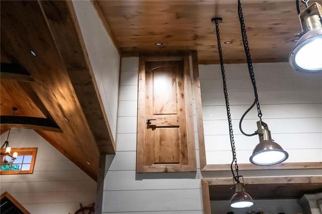 interior details with a chandelier, wooden walls, and wood ceiling