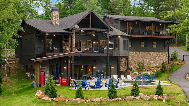 rear view of property with a yard, a balcony, and a patio