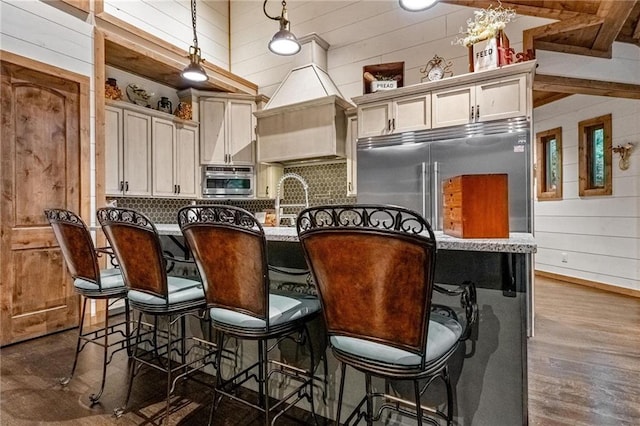 kitchen with wooden walls, decorative light fixtures, dark hardwood / wood-style flooring, and a breakfast bar