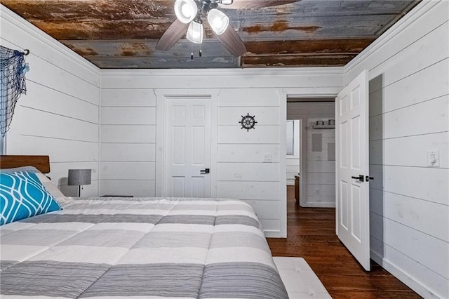 bedroom with wooden walls, ceiling fan, and dark wood-type flooring