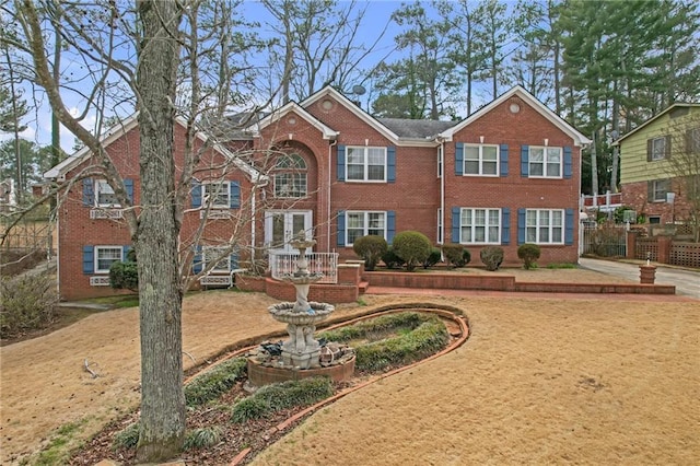 view of front of home featuring brick siding and fence