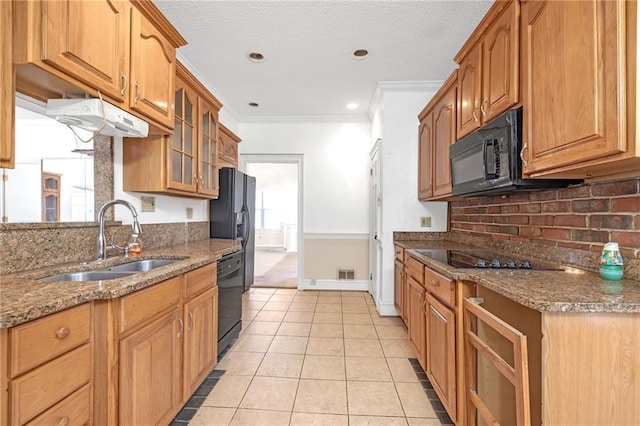 kitchen with glass insert cabinets, stone counters, black appliances, a sink, and light tile patterned flooring