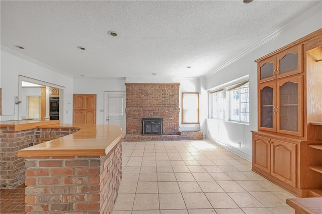 kitchen featuring glass insert cabinets, light tile patterned flooring, crown molding, and a textured ceiling