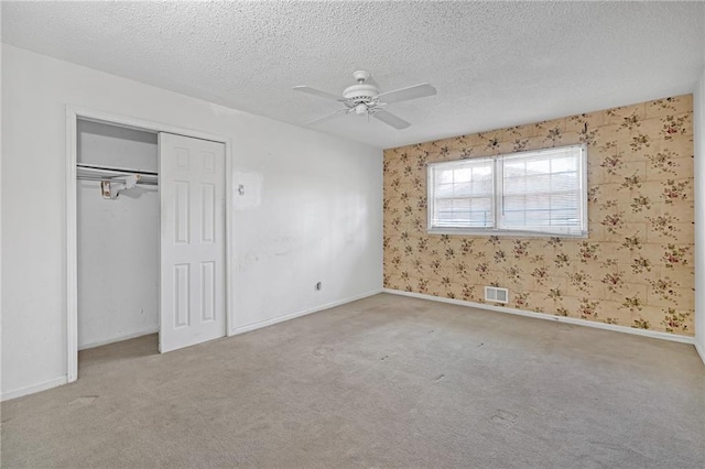 unfurnished bedroom featuring a textured ceiling, visible vents, and carpet flooring