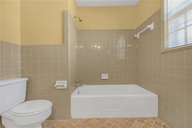 bathroom with toilet, tile patterned flooring,  shower combination, and tile walls