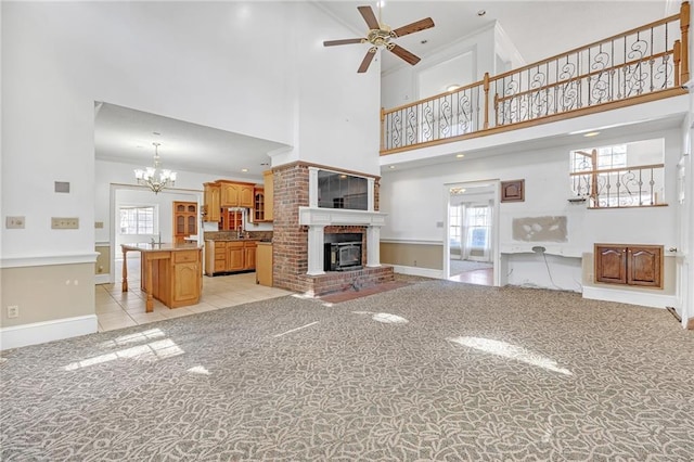 unfurnished living room featuring light carpet, plenty of natural light, a fireplace, and ceiling fan with notable chandelier