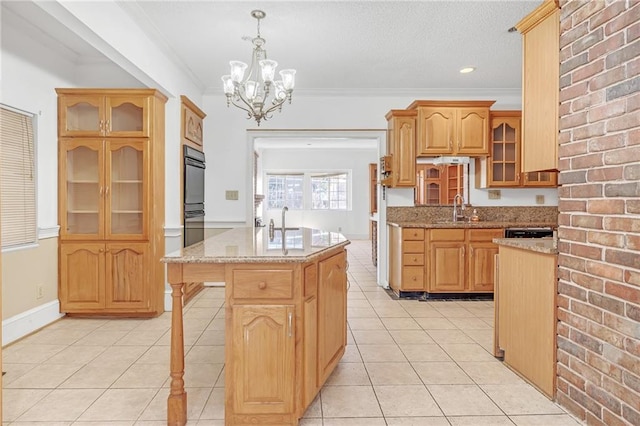 kitchen with ornamental molding, a sink, light stone counters, and light tile patterned floors