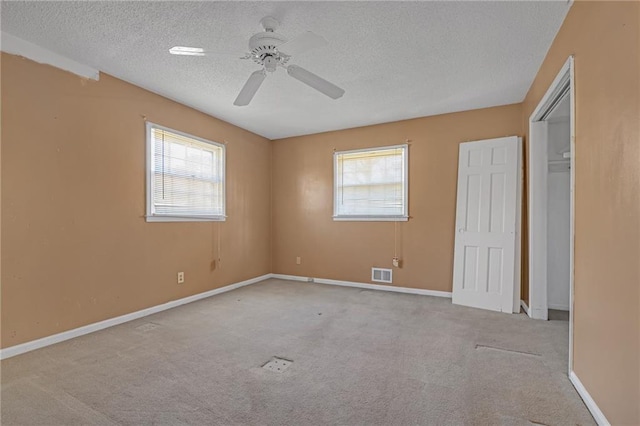 unfurnished bedroom with visible vents, a textured ceiling, baseboards, and multiple windows