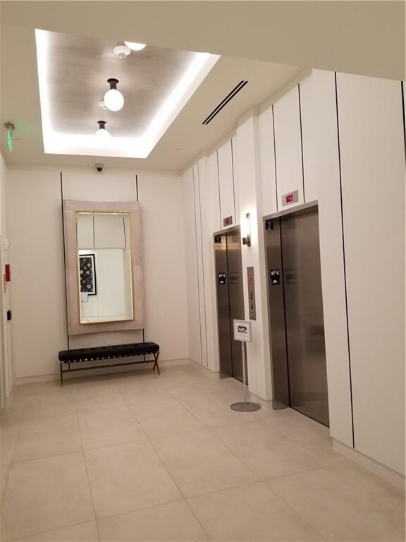 hallway with a raised ceiling and elevator