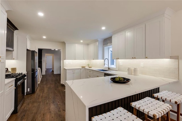 kitchen with sink, a kitchen breakfast bar, kitchen peninsula, and gas stove