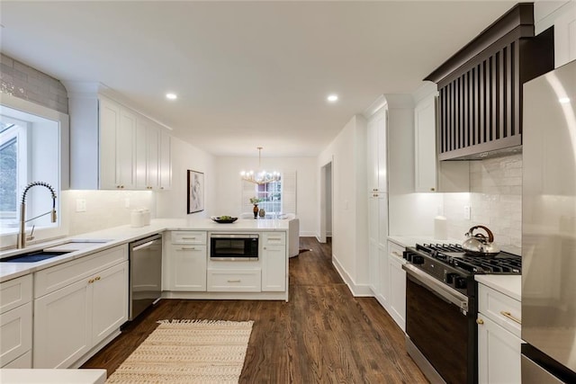 kitchen featuring stainless steel appliances, sink, white cabinets, and decorative light fixtures