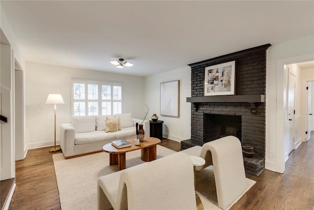 living room with a brick fireplace and hardwood / wood-style flooring