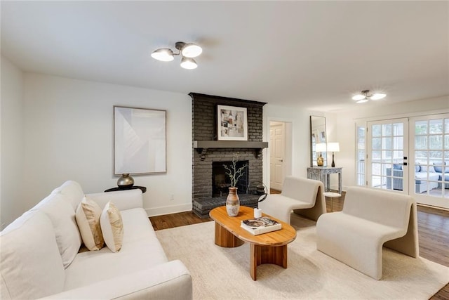 living room with wood-type flooring, a fireplace, and french doors