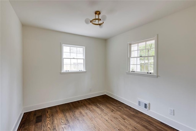 spare room with dark wood-type flooring and a wealth of natural light