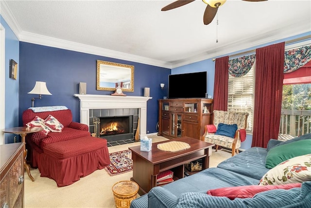 living room with carpet flooring, ceiling fan, crown molding, and a tiled fireplace