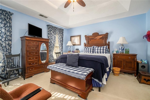 carpeted bedroom with a tray ceiling and ceiling fan