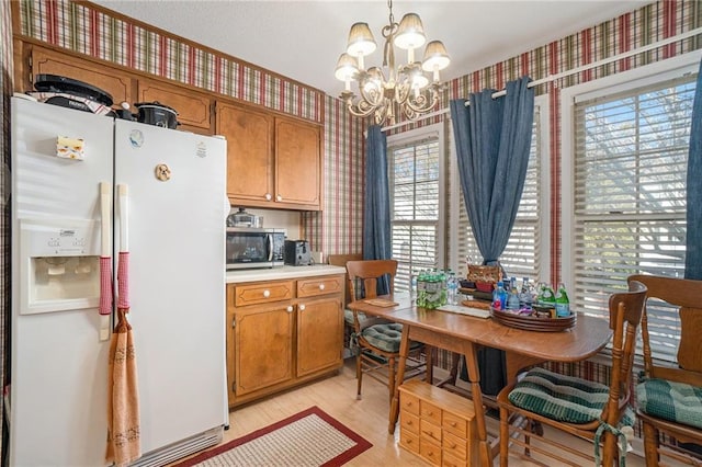 kitchen with a chandelier, decorative light fixtures, white fridge with ice dispenser, and light hardwood / wood-style floors