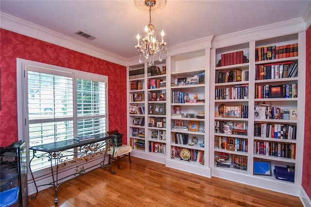 1173 Saint Charles Pl, Gainesville, GA 30501 - sitting room with wallpapered walls, wood finished floors, a chandelier, bookshelves, and crown molding