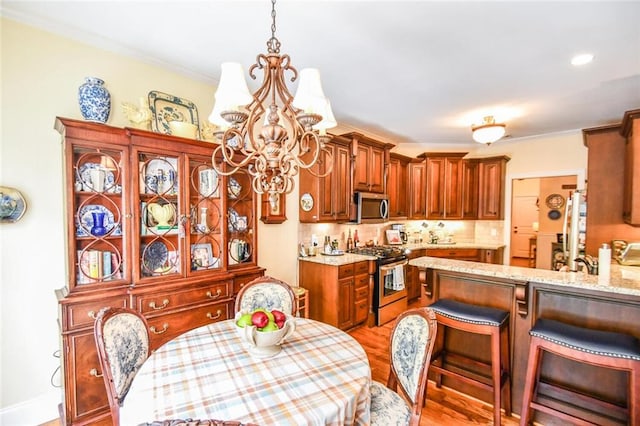 1173 Saint Charles Pl, Gainesville, GA 30501 - kitchen with stainless steel appliances, a chandelier, light wood-style flooring, decorative backsplash, and light stone countertops