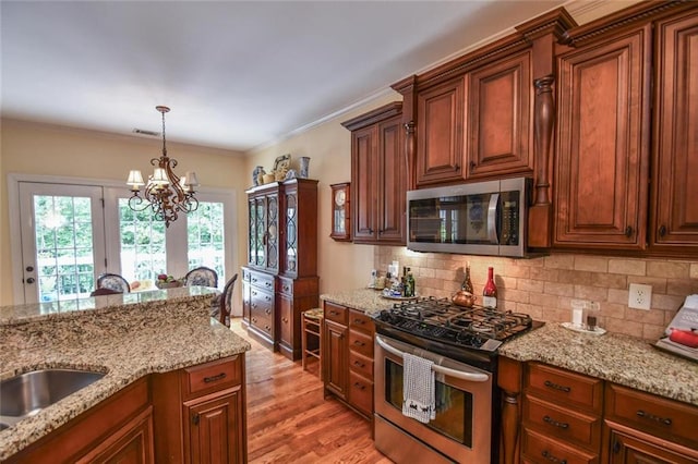 1173 Saint Charles Pl, Gainesville, GA 30501 - kitchen featuring appliances with stainless steel finishes, a chandelier, backsplash, light wood-style flooring, and ornamental molding