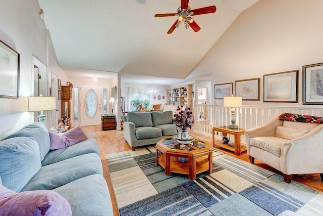 living room featuring high vaulted ceiling, an inviting chandelier, and hardwood / wood-style floors